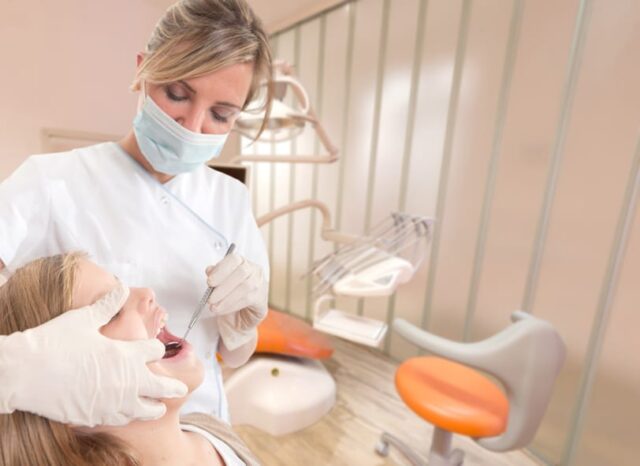 A dentist holding a mirror in a young patient's mouth