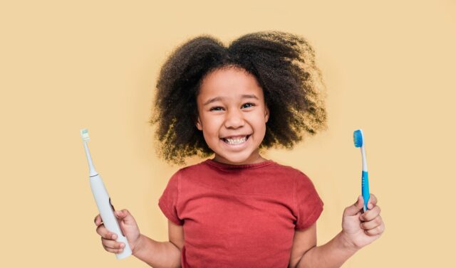 Young female patient at Summit Family and Cosmetic Dentistry chooses between an electric toothbrush and a manual toothbrush.