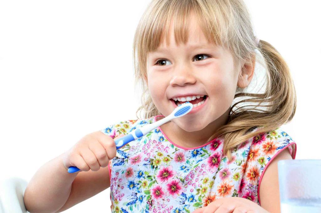 A little girl brushes her teeth to prevent cavities, as recommended by Summit Family & Cosmetic Dentistry
