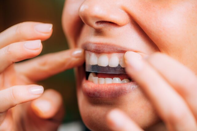person using teeth whitening strips at home in spokane