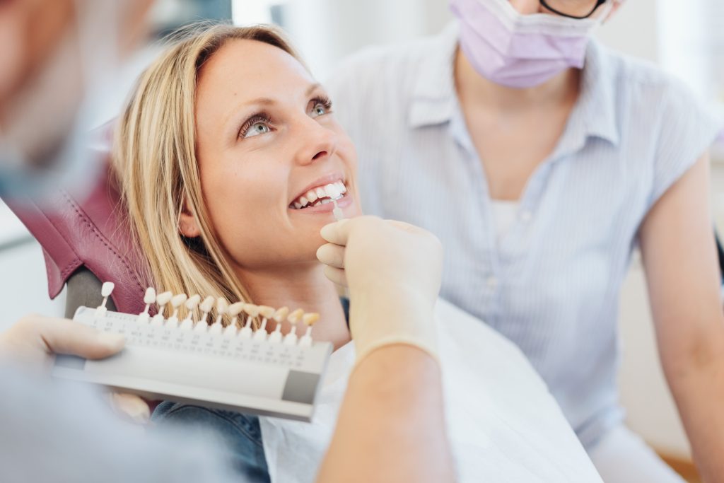 Dentist checking the whiteness of a patients teeth for veneer application