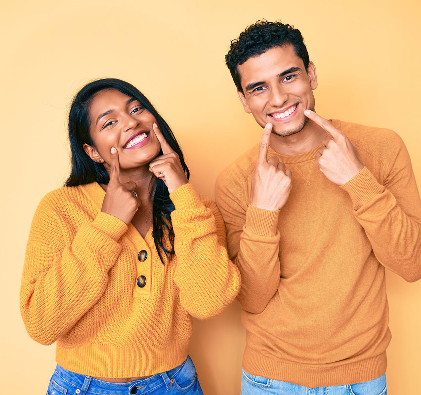two patients smiling at pointing to their new smiles