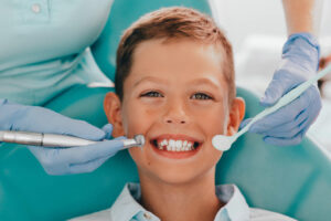 young boy having teeth evaluated by dental assistant 